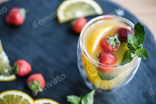 Preview: close-up view of refreshing summer cocktail with strawberries and mint on slate board