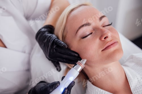 Preview: Young woman lies with her eyes closed during hardware moisturizing of the facial skin