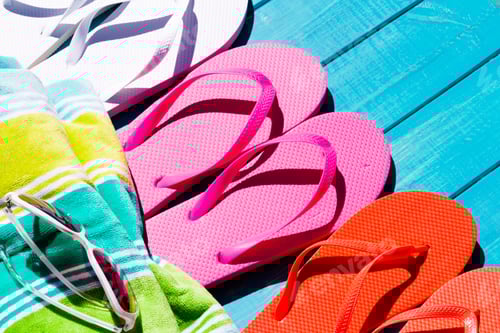 Preview: Colorful Flip Flops and Towel on Blue Surface