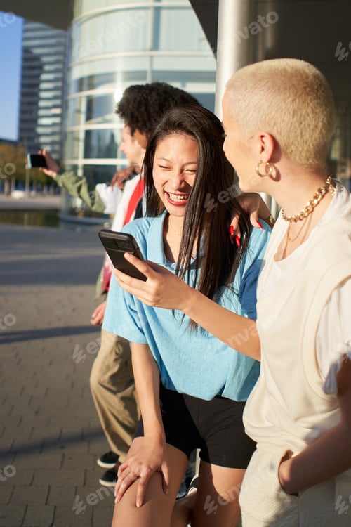 Preview: Vertical photo of a Group of happy friends using the mobile in the street