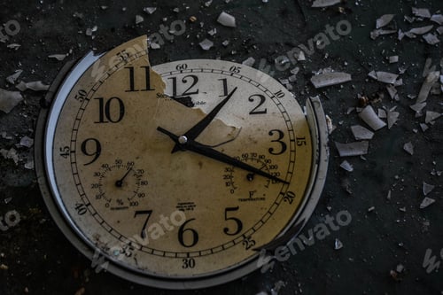 Preview: Closeup shot of a broken clock with the shards flown apart on the ground