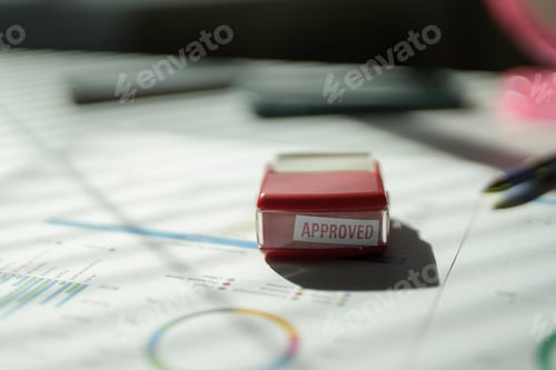 Preview: Red approved stamp lying on business documents with charts and graphs