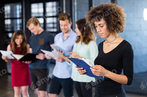 Preview: Woman looking at clipboard while her colleagues standing behind her in office