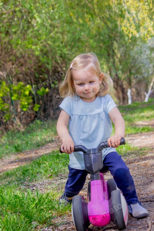 Preview: Little girl riding a balance bike. nature.