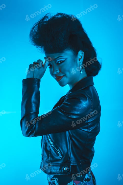 Preview: A closeup of a sexy cool hipster girl in a black leather jacket posing at the camera in blue lights