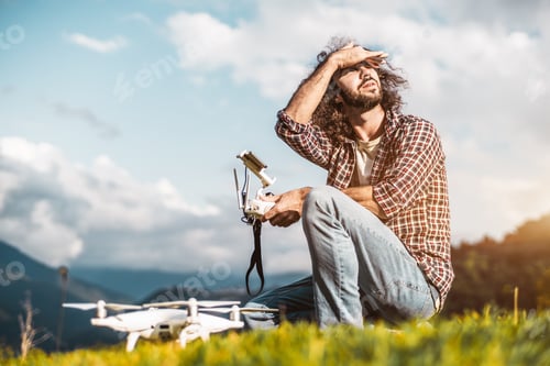 Preview: The man with quadcopter and remote controller outdoors in mountains