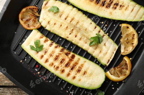 Preview: Delicious grilled courgette slices with spices and lemon in pan on table, top view