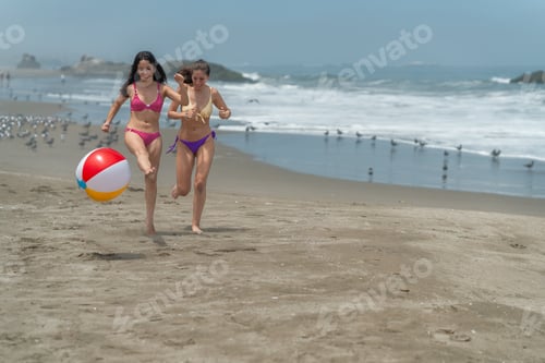 Preview: Friends having fun with beach ball running along the beach