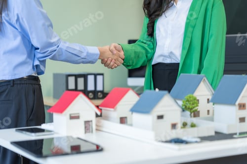 Preview: Two businesswomen sit at a table in the office,discussing a model village with windmills