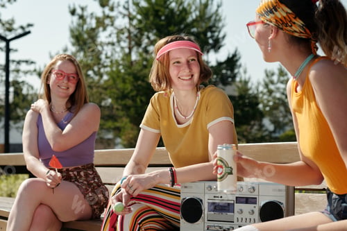 Preview: Young smiling woman looking at one of her friends during break in park