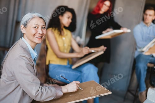 Preview: Mature teacher drawing with her students during class in art school