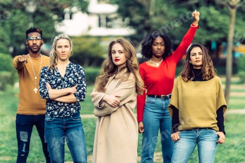 Preview: young blonde woman, wearing a coat, looks intensely at the camera in front of 4 people.