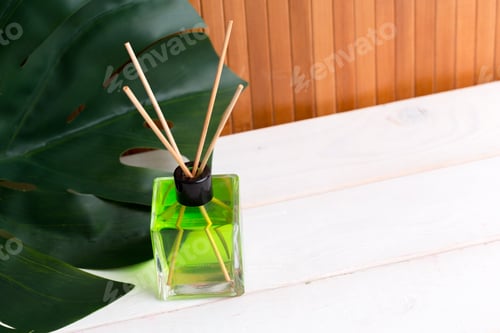 Preview: Decorative diffuser with green liquid and bamboo sticks on wooden table