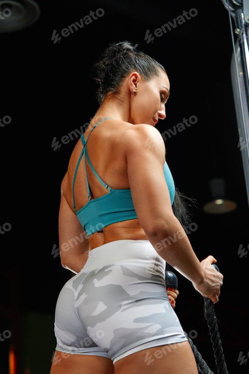 Preview: Muscular woman in gym showing back muscles. Strong fitness girl working out.