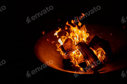 Preview: fire plate with stack of wood.Glowing ash and burning wood in an iron fire bowl.big bonfire in an