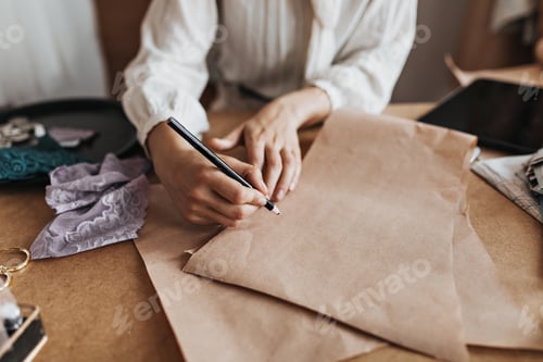 Preview: Woman in white blouse draws sketch. Lady in stylish blouse designing and creating clothes samples.