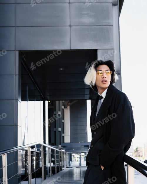 Preview: Stylish ethnic businessman in coat against urban building