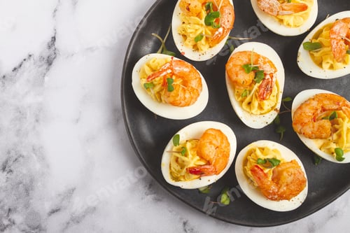 Preview: Boiled eggs stuffed with yolk and seasoned with mayonnaise,stuffed eggs with shrimp,on a black plate