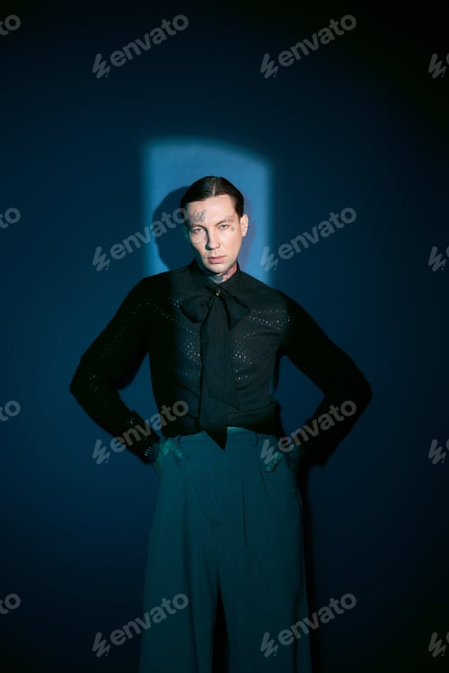 Preview: Stylish young man exuding confidence in a dark setting with striking blue accents