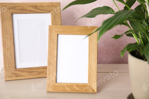 Preview: Spathiphyllum plant and photo frames on table near color wall, space for design. Home decor