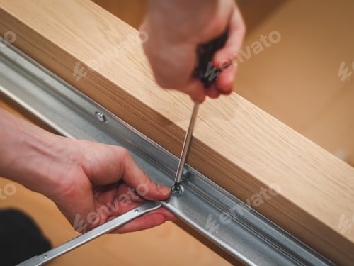 Preview: The hands of a caucasian young man twisting a screw with a screwdriver connecting a metal part to a