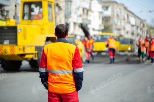 Preview: An employee in an orange uniform controls the process of road repairs.