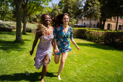 Preview: Two multiethnic women running holding hands outdoors