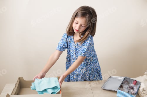Preview: Cute Caucasian little girl organizing her clothes for donation and reusing