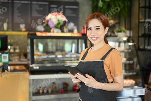 Preview: Half length of beautiful asian female entrepreneur in apron standing in modern cafe interior.