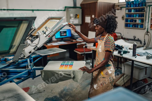 Preview: Interracial female printing shop worker finishing silk screen printing