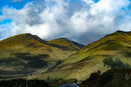 Preview: White car is travelling along a curving road in a rural landscape