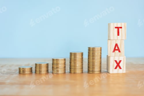 Preview: Up golden coin stack on wooden desk with word "TAX" on wood block.