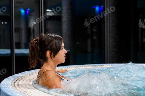 Preview: Side view of attractive young relaxing in whirlpool in spa