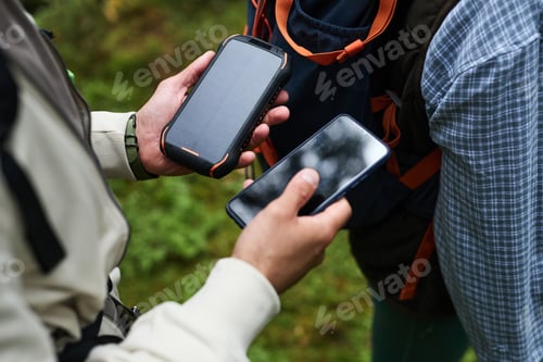 Preview: Young Adult Men Using Smartphone and Solar Power Bank While Hiking Outdoors