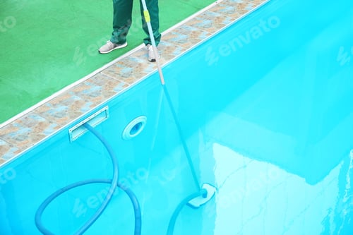 Preview: Male worker cleaning outdoor pool with underwater vacuum