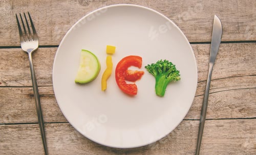 Vegetable Slices Spelling Diet on Plate with Utensils