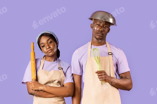 Preview: Exhausted black couple with kitchen utensils having hard time baking on color background