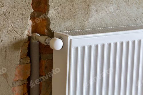 Preview: Close-up side view of isolated installed heating radiator on brick rough plastered wall