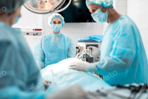 Preview: Waist Up Portrait Of Young Lady In Protective Mask And Sterile Gown Watching How Doctor Doing