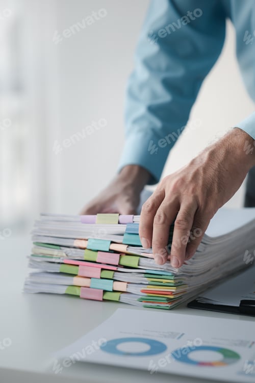 Preview: A person in an office with a huge stack of papers, he is a company employee, managing paperwork and