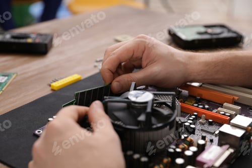 Preview: Male technician repairing motherboard at table, closeup