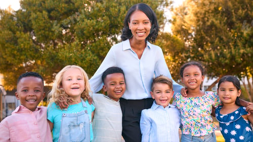 Preview: Portrait Of Female Primary Or Elementary School Teacher With Multi-Cultural Class Outdoors