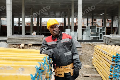 Preview: Serious mature black man in workwear and protective helmet looking at camera