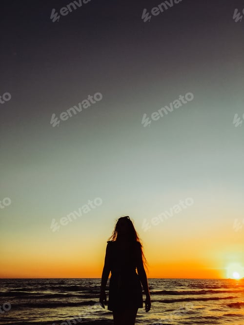 Preview: Silhouette of a beautiful woman in front of a sunset. In golden hour.