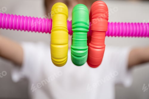 Preview: anti stress sensory pop tube fidget toy in kid's hands. little happy child boy plays with poptube