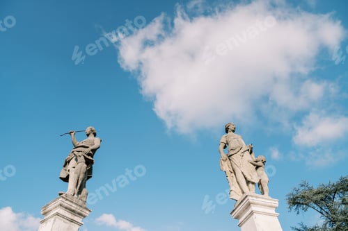 Preview: Ancient statues on stone pedestals of the fence of an old villa against a blue sky