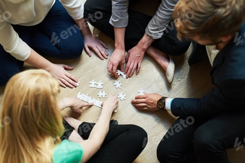 Preview: Piecing it together. Shot of a group of people putting a puzzle together.