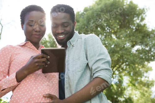 Preview: Couple using digital tablet in park