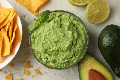 Preview: Concept of tasty eating with guacamole and chips on white textured background, top view