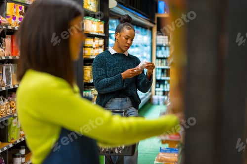 Preview: Customer reading label on product in organic supermarket